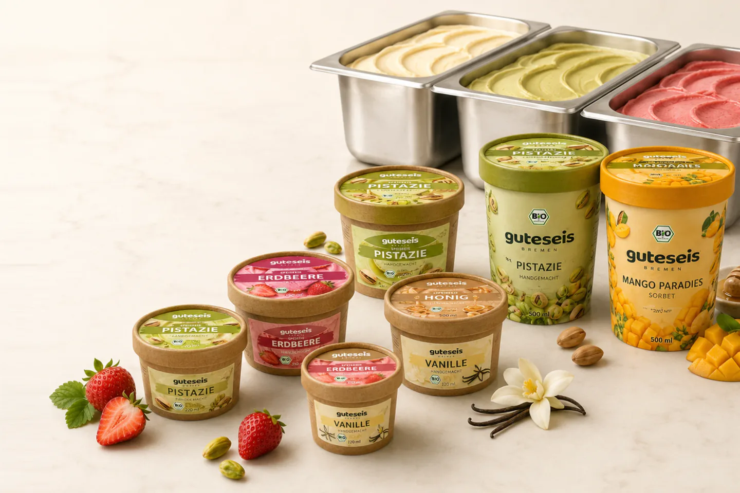 Guteseis Bio-Becher in mehreren Größen vor drei offenen 5-Liter-Edelstahl-Gastronomiewannen mit Vanille-, Pistazien- und Erdbeereis – AI Generated